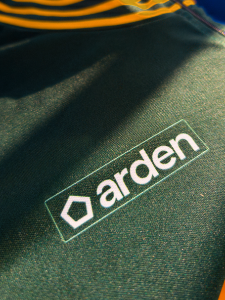 Détail de maillot vert ArdenSport avec motifs feuillus et col orné d'épis de blé dorés – design personnalisé